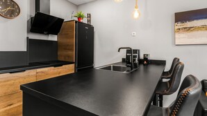 A modern kitchen with a central island, black appliances, and a wooden accent wall.