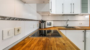 A modern kitchen with white cabinets, a wooden countertop, a built-in microwave, and a stainless steel sink.
