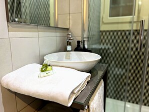 Kylpyhuone, jossa on valkoinen pesuallas, pyyhe ja pullo shampoota.