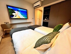 Hotellihuone, jossa on sänky, seinälle asennettu televisio, työpöytä ja vaatekaappi.
