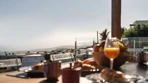 Ein Frühstückstisch mit Croissants, einem Glas Orangensaft und Blick auf eine Stadtlandschaft mit Gebäuden und Bergen im Hintergrund.