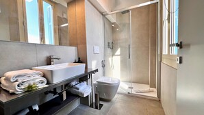 Ein modernes Badezimmer mit Duschkabine aus Glas, einem großen Spiegel und einem Waschtisch mit Spüle und Handtüchern.