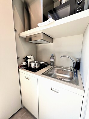 A compact kitchen with a stainless steel sink, a stove, and a microwave. - MyResidenced'Azur - appartement 7A (Beausoleil)