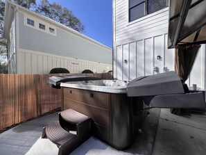 Un bain à remous avec une terrasse et des marches en bois, une clôture en bois et une maison en arrière-plan.