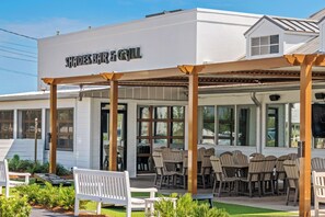 A restaurant with outdoor seating, covered by a pergola, and a sign reading "Shores Bar & Grill".