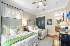 A bedroom with two beds, a ceiling fan, and a nightstand with a lamp.