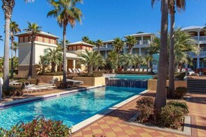 A pool area with lounge chairs and palm trees.