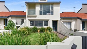 A modern two-story house with a red-tiled roof, large windows, and a well-maintained garden.
