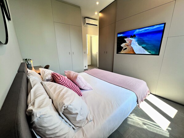 Une chambre à coucher avec un lit, un téléviseur fixé au mur et une armoire.