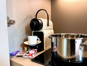 Une machine à café, une tasse, une théiÚre et quelques barres de chocolat sur un comptoir.