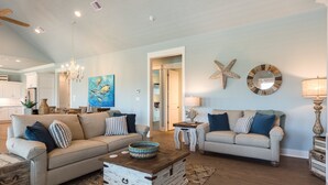 A spacious living room with two sofas, a coffee table, and a chandelier. - Ocean View | Modern Interior l Tiki Bar l Pet-Friendly (Crystal Beach)