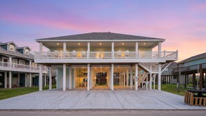 A two-story house with a covered front porch and a balcony. - Ocean View | Modern Interior l Tiki Bar l Pet-Friendly (Crystal Beach)