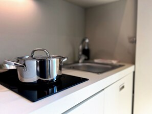 A kitchen with a stove, a sink, and a white countertop.