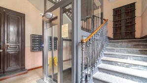 A grand staircase with ornate balusters, a wooden door, and a glass entrance with a sign.