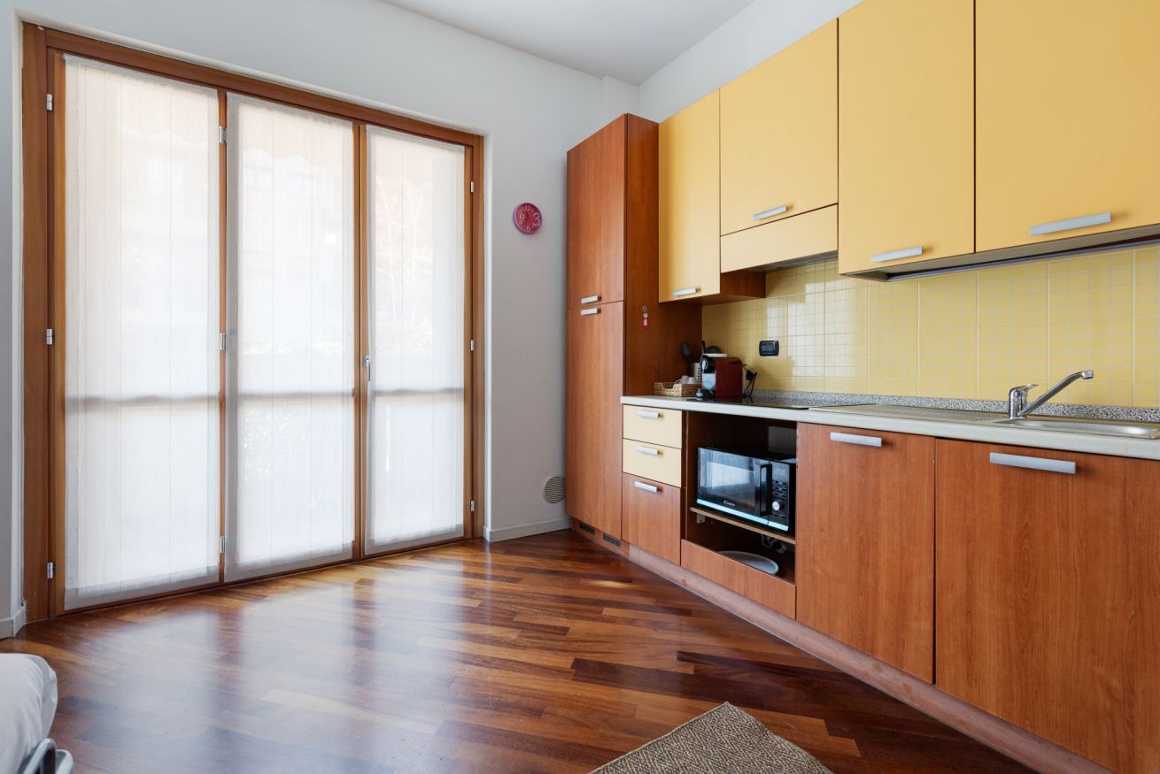 Eine Küche mit Holzausstattung, einem Einbauofen und einer Schiebetür aus Glas.