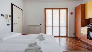 Una camera d'albergo con un letto, un armadio in legno, un termosifone e una porta scorrevole in vetro.