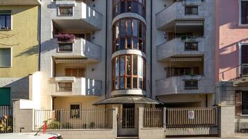 Un edificio a più piani con balconi, una sezione cilindrica centrale e un ingresso chiuso da cancello.