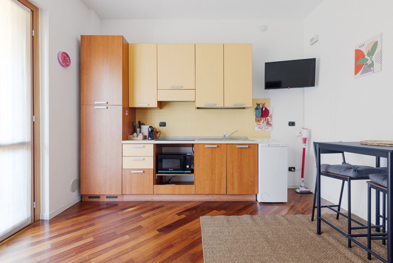 A compact kitchen with wooden cabinets, a microwave, and a small refrigerator.
