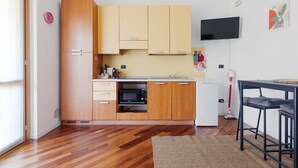 Une cuisine de taille réduite, dotée de meubles en bois, d’un four à micro-ondes et d’un petit réfrigérateur.