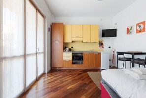 A compact kitchen with wooden cabinets, a microwave, and a small refrigerator.