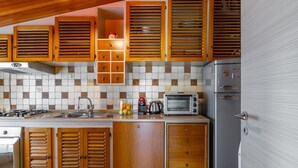 Una cocina con armarios de madera, salpicadero de azulejos, estufa a gas, microondas y refrigerador.