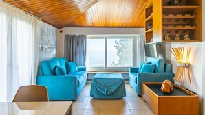 Una sala de estar moderna con dos sofás azules, una mesa de centro de madera y una estantería con objetos decorativos.