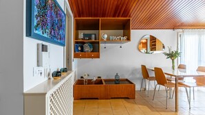 Un interior moderno con techo de madera, estante empotrado con objetos decorativos, comedor con sillas y un espejo grande.