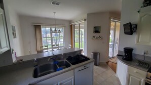 A kitchen with a large island, a dishwasher, a coffee maker, and a view of the outdoors through large windows. - Parker Lakes Heated Pool, Spa and Sports Park <8 miles to Beach, Margaritaville. (Fort Myers)