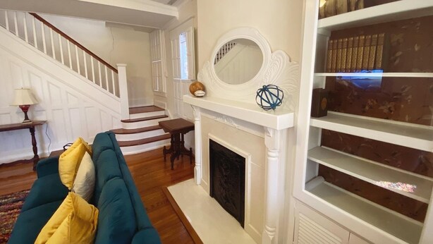 A living room with a fireplace, a staircase, and a bookshelf. - NEW 4 bed/4.5 Bath Historic Home in the Boro-Walking Distance to the Square (Murfreesboro)