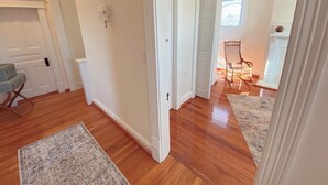 A hallway with wooden flooring, white walls, and a door leading to another room. - NEW 4 bed/4.5 Bath Historic Home in the Boro-Walking Distance to the Square (Murfreesboro)