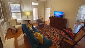 A living room with a sofa, chairs, a television, and a patterned rug. - NEW 4 bed/4.5 Bath Historic Home in the Boro-Walking Distance to the Square (Murfreesboro)