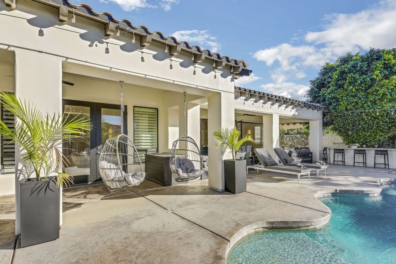 Un espace piscine extérieur moderne, agrémenté d’une pergola, de chaises longues et d’un jardin bien entretenu.