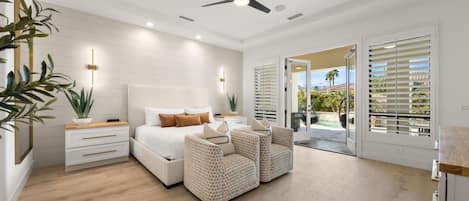 A modern bedroom with a bed, bedside tables, a seating area, and a view to an outdoor space.