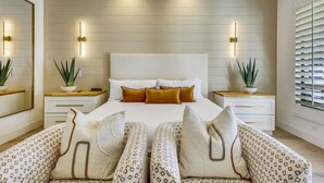 A modern bedroom with a large bed, two bedside tables with lamps, a large mirror, and a window with blinds. - Santana: Pool, Spa, BBQ, Fire Pit, Cabanas, Games! (Indio)