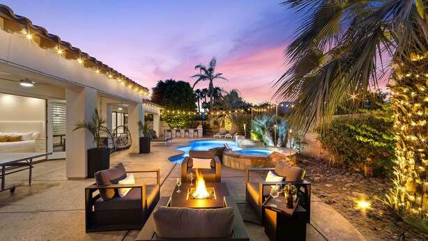 A poolside area with outdoor seating, a hot tub, and string lights. - Santana: Pool, Spa, BBQ, Fire Pit, Cabanas, Games! (Indio)