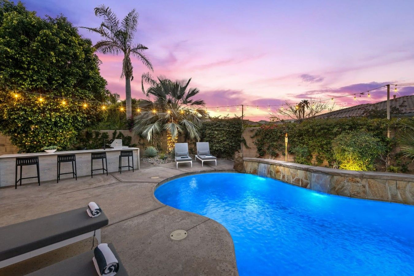 Ein Pool mit geschwungener Kante, umgeben von Liegestühlen und einer Bar.