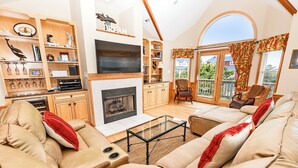 Un salón amplio con chimenea, asientos cómodos y un ventanal con vistas al exterior.