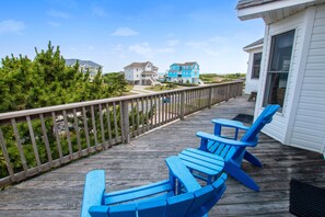A wooden deck with blue Adirondack chairs, a wooden railing, and a view of houses and trees. - Semi-Oceanfront, Private Pool, Ocean Views, Close to beach! WL808, Beach Dreams (Corolla)