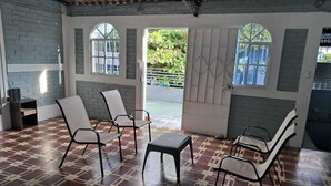 Una habitación con piso de baldosas, varias sillas, una mesa y una puerta que da al exterior.