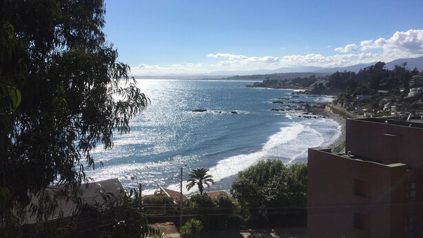 A coastal view with a clear sky, a beach, and residential buildings. - Cabaña con Balcón y Vista al Mar (Concón)