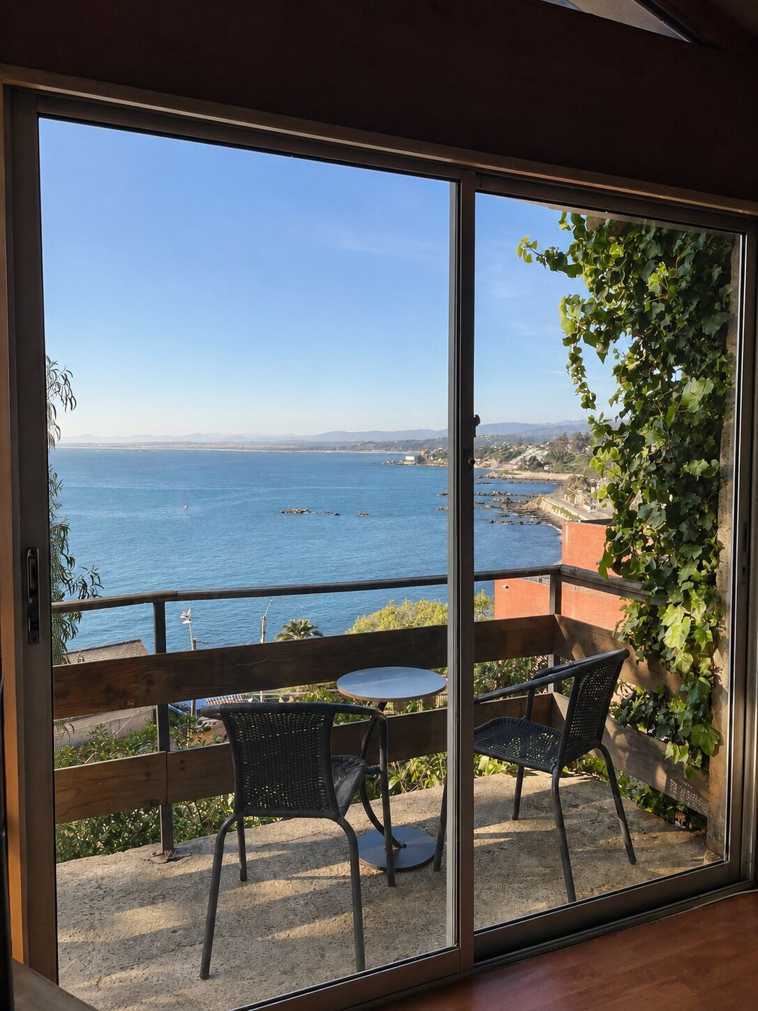 Varanda com vista para o mar, uma mesa e duas cadeiras.