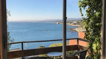 Varanda com vista para o mar, uma mesa e duas cadeiras.