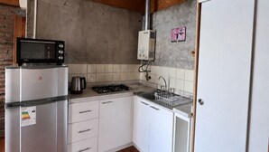 Una cocina compacta con microondas, estufa y refrigerador integrados.