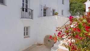 A white building with multiple windows and a stone wall. - 4 bedrooms, sea views, and pure relaxation in Frigiliana. (Frigiliana)