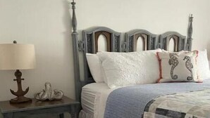 Ein Schlafzimmer mit einem hölzernen Kopfteil, einem Nachttisch mit Lampe und einem Bett mit Decke.