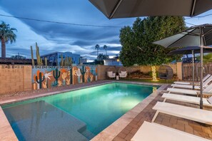 A swimming pool with lounge chairs and a mural of cacti. - Closest Walk to Entertainment District (Scottsdale)