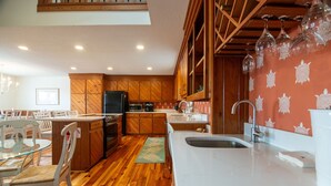 A modern kitchen with wooden cabinets, a built-in oven, and a large island with a sink. - Lost Options-Premier Home w/ Tidal Creek Dock; Creek/Marsh Views; Easy Beach Access (Edisto Beach)