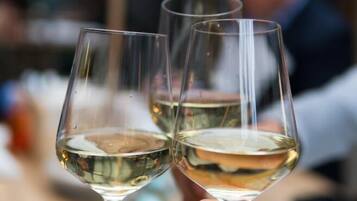 Two wine glasses filled with white wine, held by hands.