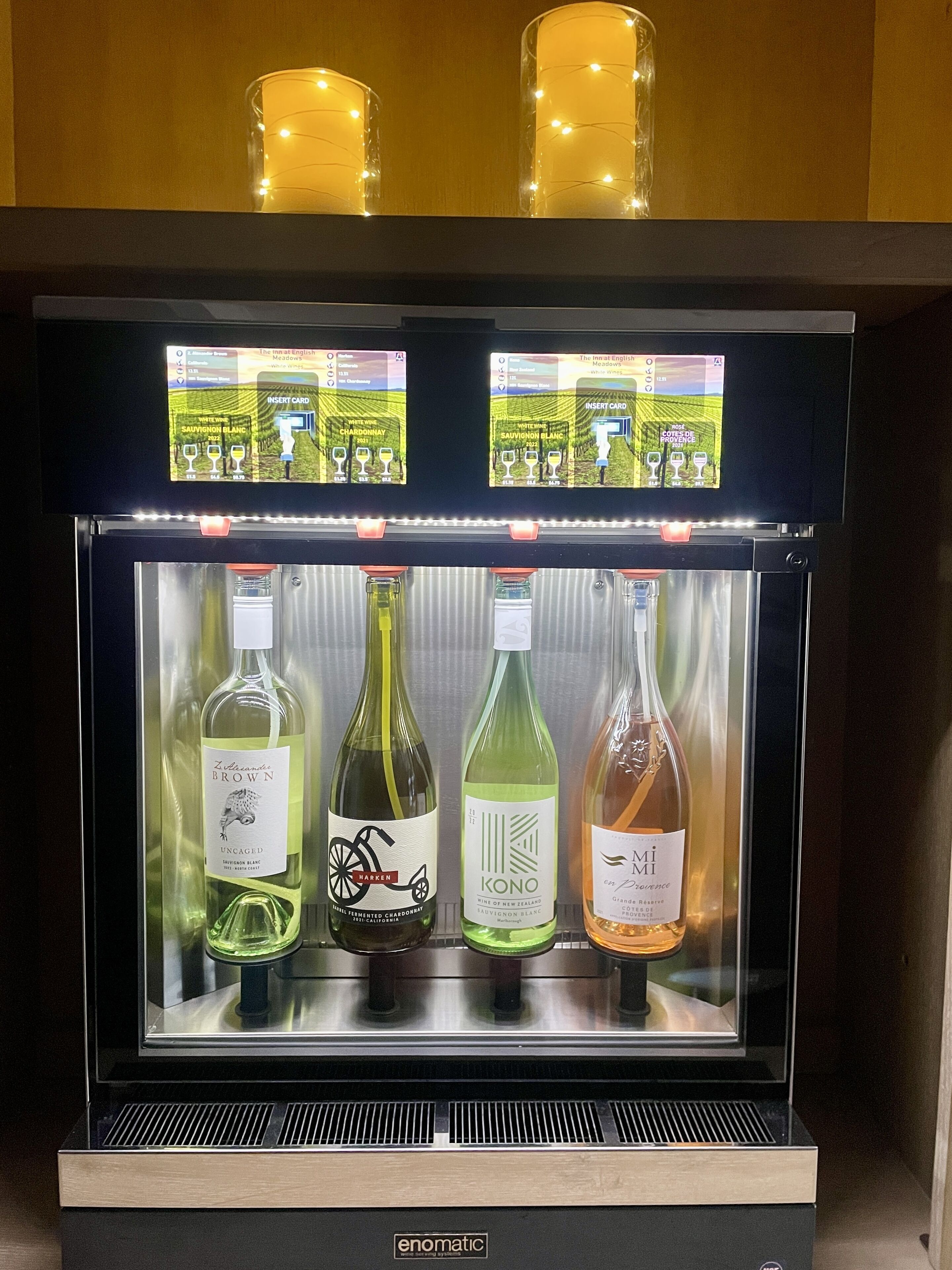 A refrigerated display case with four bottles of wine, each with a label and a price tag.