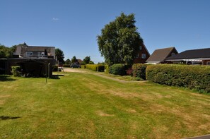 A residential area with a well-maintained lawn, a large tree, and houses with visible driveways.